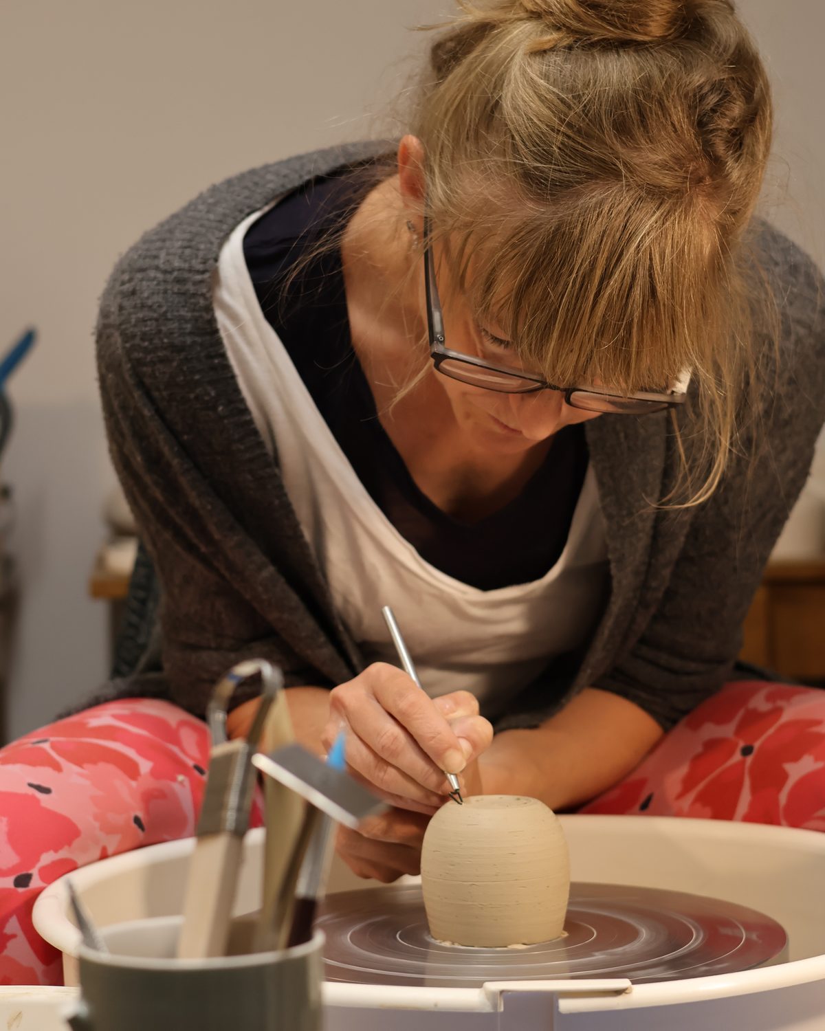 Liza shaping a piece at the pottery wheel